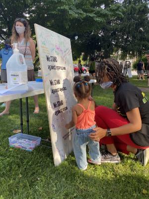 Woman and toddler signing the Community Commitment Mural