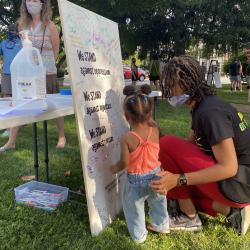 Woman and toddler signing the Community Commitment Mural