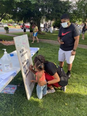 Helping a little girl sign the Community Commitment Mural