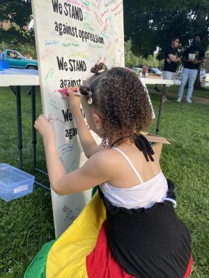 Young girl signing the Community Commitment Mural