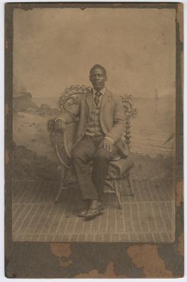 Mr. Hynson sitting on fancy chair with painting behind him
