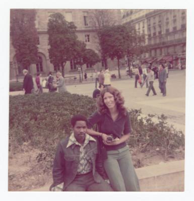 Two people posing in front of a large building
