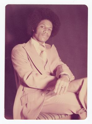 A man posing in a tan suit