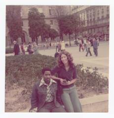 Two people posing in front of a large building