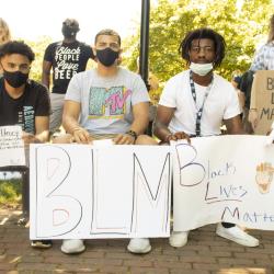 Four young adults holding protest signs