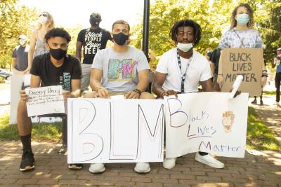 Four young adults holding protest signs